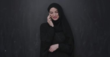 Modern Müslüman kadın siyah karatahta üzerinde akıllı telefon kullanıyor