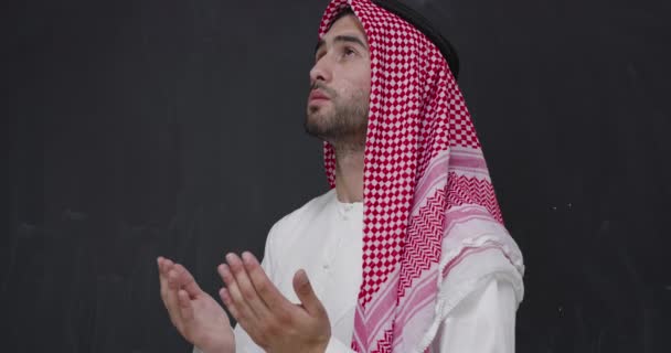 身穿传统服装的阿拉伯年轻人向上帝祈祷 在黑色黑板前保持双手祈祷的姿势 — 图库视频影像