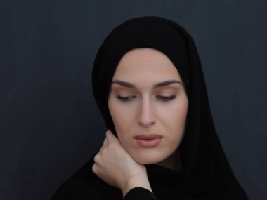 Siyah abaya giymiş modern müslüman bir kadının portresi. Geleneksel kıyafetler giyen ve siyah karatahtanın önünde poz veren Arap bir kız. Modern ve zengin Arap yaşam tarzını temsil ediyor