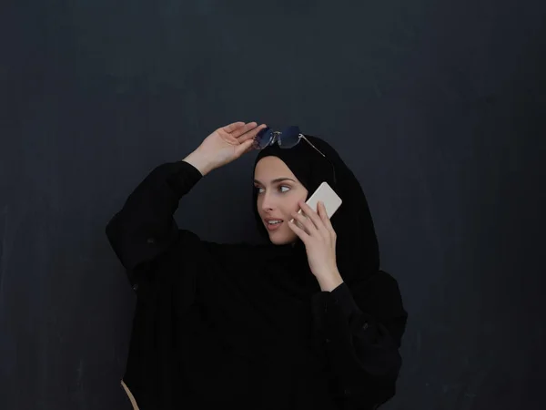 若いイスラム教徒のビジネス女性は 伝統的な服や携帯電話で話してAbaya 黒の黒板の前で イスラム教のファッションとラマダーンのカレームの概念を表すアラブの女性 — ストック写真