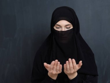 Niqab 'ın dua ettiği genç Müslüman kadın portresi. Abaya giyen Arap kız dua ederken el ele tutuşuyor. Tanrıya ibadet ve Ramazan Kareem kavramını temsil etmek