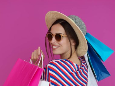 Pembe arka planda alışveriş torbaları olan genç bir kadın. Büyük bir satış gününden sonra yeni alışverişlerle poz veren mutlu kız. Kara Cuma konsepti