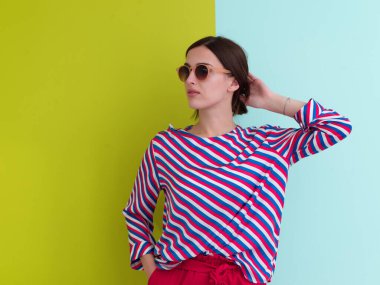 Stüdyoda poz veren genç bir kadının portresi. Renkli bir arka planda duran kadın model. Moda ve güzellik kavramı