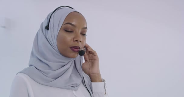 Femme d'affaires musulmane africaine représentative de la clientèle avec casque aidant et soutenant en ligne avec le client — Video
