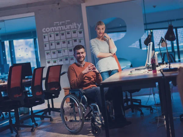 坐在轮椅上的商人在现代化的合作办公空间上工作到深夜 后面的同事们残疾和障碍概念 有选择的重点 — 图库照片