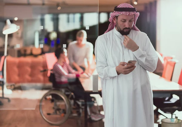 オフィス会議室で中東アラブのビジネスマンは スマートフォンで話しています 車椅子の障害者のビジネスマンは 背景のチームと協力しています 高品質の写真 フォロー — ストック写真