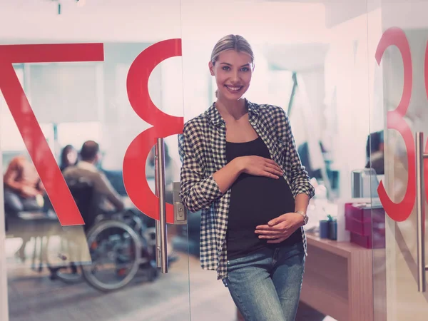 Portrét těhotné podnikatelky jemně držící břicho v moderní kanceláři — Stock fotografie