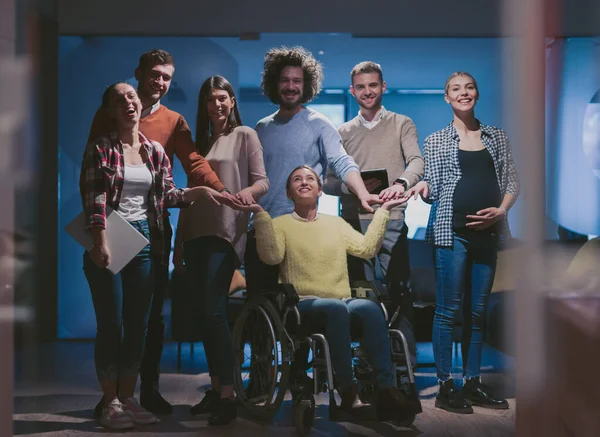 Disabled businesswoman in a wheelchair at the office with coworkers team — Stock Photo, Image