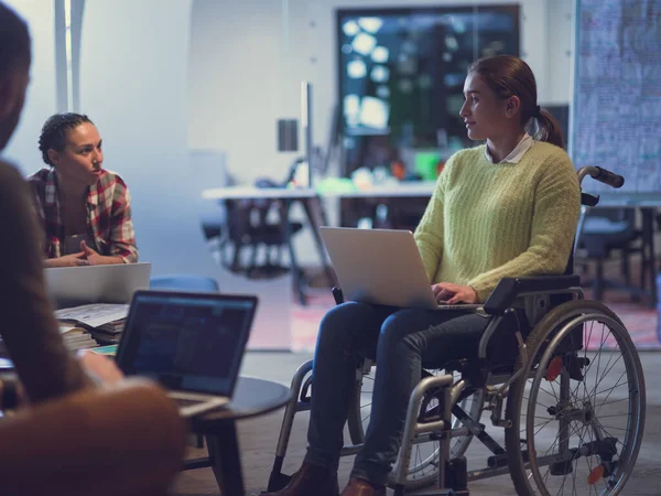 Handicapperd zakenvrouw in een rolstoel op ontmoeting met haar diverse business team brainstormen op kantoor — Stockfoto