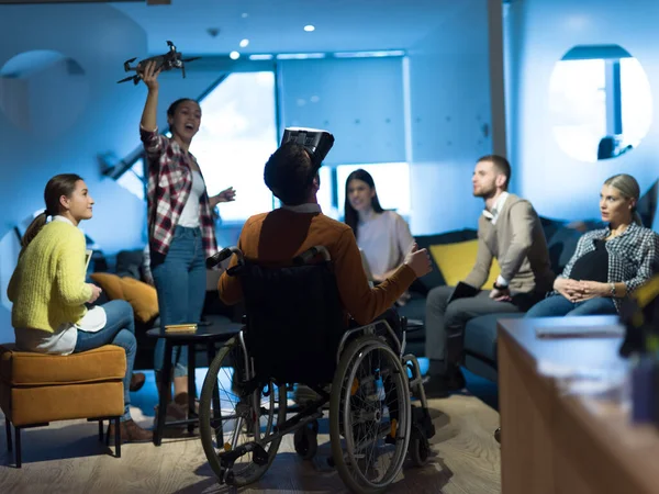 Uomo d'affari disabile in sedia a rotelle al lavoro in un moderno ufficio di coworking open space con team che utilizza la simulazione di assistenza drone googles realtà virtuale — Foto Stock
