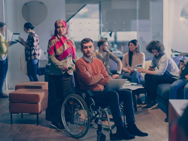 Homme d'affaires handicapé en fauteuil roulant au travail dans un bureau de coworking moderne à espace ouvert avec équipe — Photo