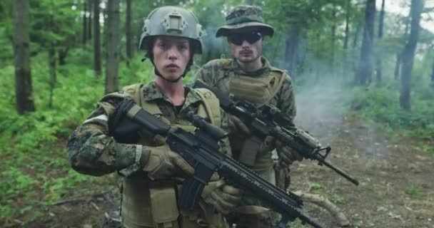 Eenheid soldaten patrouilleert door het bosgebied, team met mannelijke en vrouwelijke soldaten in dicht bos met rook in de rug — Stockvideo
