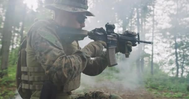 Солдат прицілюється від гвинтівки в лісі, дим на задньому плані, військова та армійська концепція — стокове відео