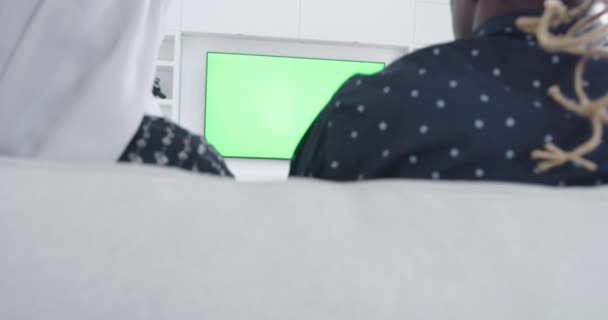 Green screen tv with african couple on sofa at home rear view — Stock Video