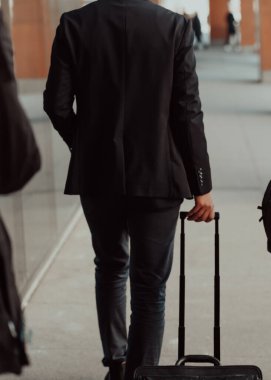 Tekerlekli bavul taşıyan bir adam sokakta yürüyor. Kadın işe gidip kahve içiyor...