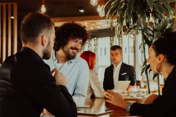 Un grupo de amigos pasando el rato en un café, y hablando de negocios —  Fotos de Stock