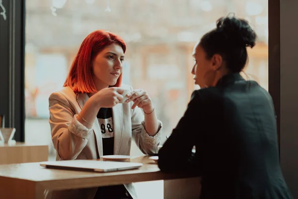 Deux jeunes femmes d'affaires assises à table dans un café.Fille utilisant un ordinateur portable, smartphone, blogging. Travail d'équipe, réunion d'affaires. Indépendants travaillant... — Photo