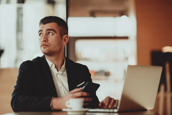 Glücklicher Geschäftsmann sitzt mit Laptop und Smartphone in Cafeteria — Stockfoto