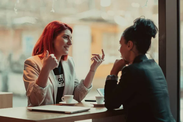 Deux jeunes femmes d'affaires assises à table dans un café.Fille utilisant un ordinateur portable, smartphone, blogging. Travail d'équipe, réunion d'affaires. Indépendants travaillant... — Photo