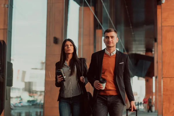 İş adamı ve iş kadını konuşuyor ve bavul taşıyor iş seyahatinde, ellerinde taze kahve taşıyorlar. İş konsepti. — Stok fotoğraf