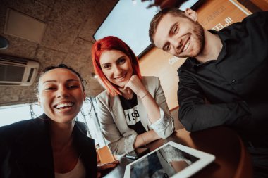 Modern bir ofiste oturan ve modern aletler kullanan genç girişimcilerin eğlenceli bir portresi.