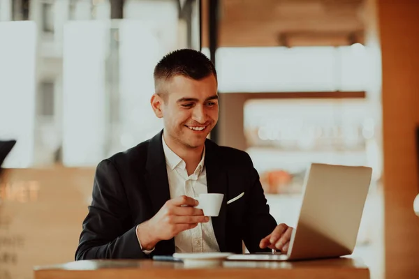 Glücklicher Geschäftsmann sitzt mit Laptop und Smartphone in Cafeteria. — Stockfoto