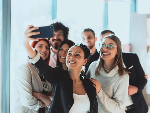 Groep vrolijke collega 's neemt selfie en gebaren terwijl ze in het moderne kantoor staan. — Stockfoto