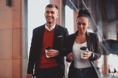 İş adamı ve iş kadını konuşuyor ve bavullarını tutuyor iş seyahatinde, ellerinde taze kahve taşıyorlar. İş konsepti. Yüksek kaliteli fotoğraf.