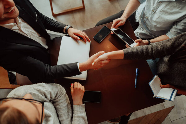Business people or lawyers shaking hands finishing up meeting or negotiation in sunny office.