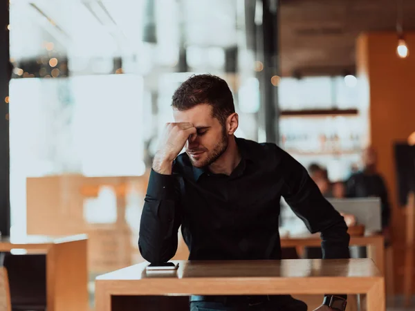 Ein müder Geschäftsmann, der in einer Cafeteria in einer Arbeitspause sitzt. — Stockfoto