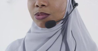 Afrikalı Müslüman müşteri temsilcisi kulaklıklı iş kadını müşteriyle çevrimiçi olarak yardım ve destek veriyor