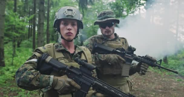 Загін солдатів, які патрулюють лісові райони, команда з чоловіками і жінками-твердими в густому лісі з димом на задньому плані — стокове відео