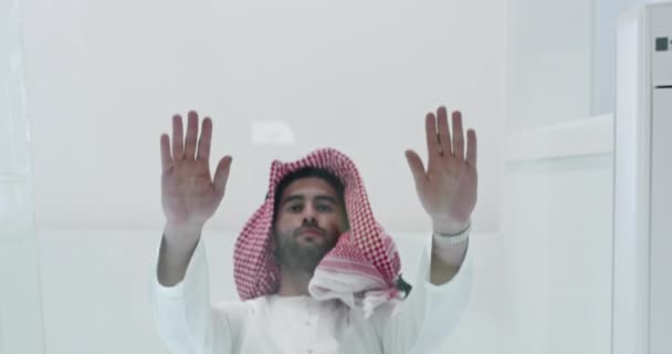 Muslim man in traditional clothes praying on the glass floor before iftar dinner — Stock Video