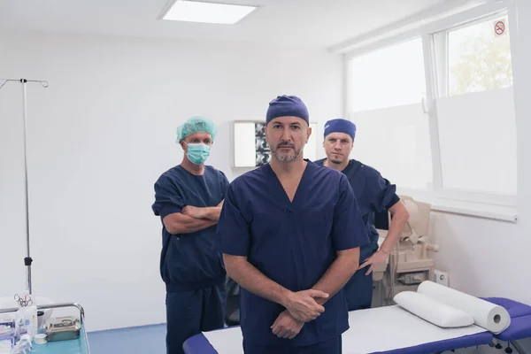 Médico ortopédico multiétnico na frente de sua equipe médica olhando para a câmera usando máscara facial — Fotografia de Stock