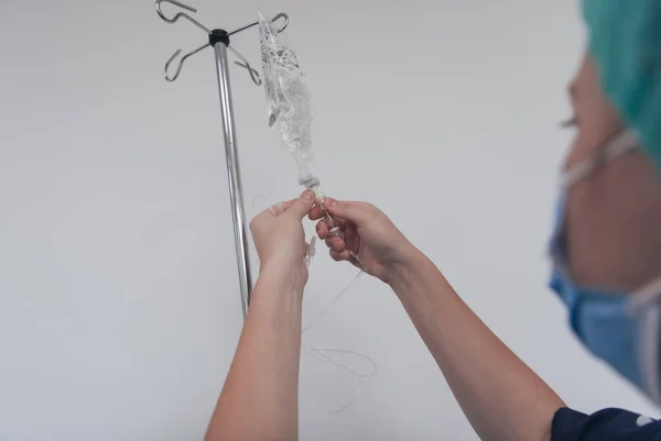 General practitioner holding intravenous drip infusion. Doctor handling IV fluid drip with copy space on white background. Nurse performing Intravenous therapy.