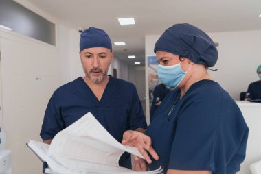 Covid-19 salgını sırasında yüz maskesi takan tıbbi çok ırklı ekibinin önünde ortopedi doktoru. Meslektaşlarının önünde cerrah. Seçici odak.