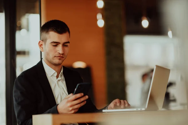 快乐的商人坐在自助餐厅里 拿着笔记本电脑和智能手机 商人坐在酒吧餐厅时 用智能手机发短信 在计算机上工作和检查电子邮件的商人 — 图库照片