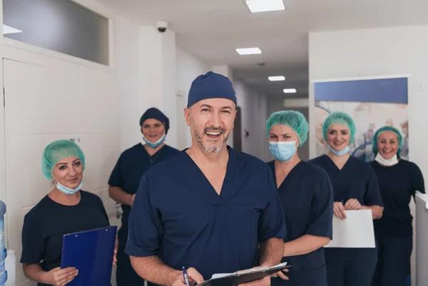 在Covid 19爆发期间 整形外科医生在他的多族裔医疗团队面前戴着口罩 外科医生在他的同事面前 有选择的重点 — 图库照片