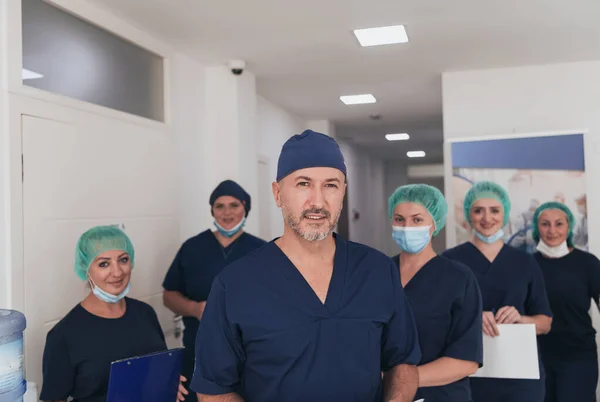 在Covid 19爆发期间 整形外科医生在他的多族裔医疗团队面前戴着口罩 外科医生在他的同事面前 有选择的重点 — 图库照片