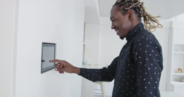 スマートホームアプリケーションのための壁に家庭用制御システムを使用して黒人アフロアメリカ人男性 — ストック動画