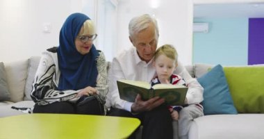 Geleneksel Müslüman aile büyükbabaları ve çocukları Kuran okuyup evdeki kanepede birlikte dua ediyorlar. 