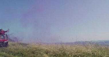 Hippi arkadaşlar doğada off-road araba sürerken renk fişekleriyle eğleniyorlar. Maceracı ruh ve özgürlük