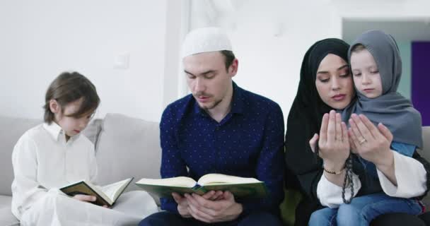 在斋月期间 传统的穆斯林家庭父母带着孩子在沙发上一起诵读 古兰经 和祈祷 — 图库视频影像