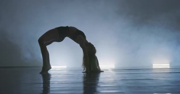 スモーキーな雰囲気の中で練習する現代バレエダンサー 芸術舞踊の練習中にスレンダーな柔軟なダンスパフォーマー — ストック動画