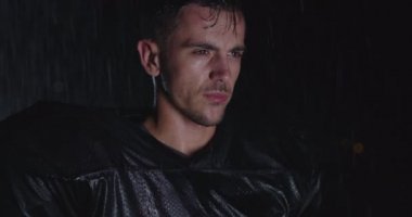 Karanlıkta yağmur yağarken topu tutan kararlı profesyonel Amerikan futbolcusunun portresi. Spor üniformalı kendine güvenen bir adam. ABD takım oyunu ve ekstrem spor ruhu konsepti. 