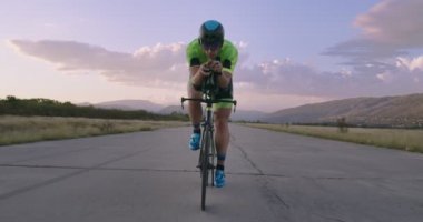 Profesyonel bir yarış bisikletine binen triatlon sporcusunun gece bisikleti eğitimi. Akşamları virajlı bir yolda sağlıklı ve yoğun bir egzersiz. Yavaş çekim izleme çekimi. 