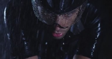 Triatlon atleti, yağmurlu bir karanlıkta yoğun bir idmanda profesyonel bir yarış bisikletine biniyor. Yağmurlu bir gecede kötü hava koşullarında antrenman ya da yarışma. Ağır çekim. Merhaba kaliteli 4K görüntüler