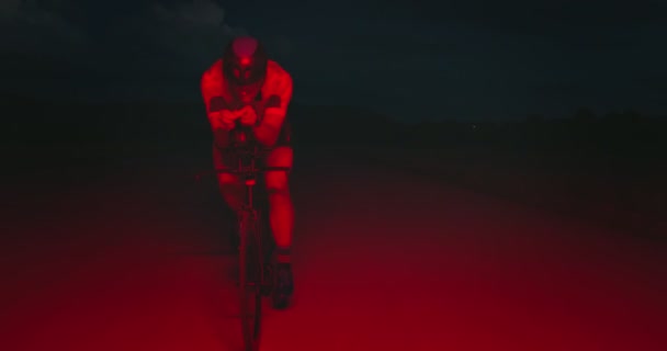 プロのレーシングバイクに乗ってトライアスロン選手の夜の自転車トレーニング 夕方には曲がりくねった田舎道で健康的な強烈なワークアウト スローモーショントラッキングショット — ストック動画