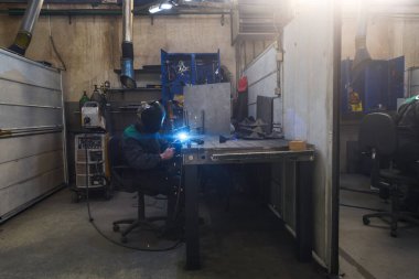 Profesyonel kaynakçı fabrikalarda, kıvılcımlarda ve elektrikte metal parçalarıyla iş yapıyor. Sanayi işçisi afişi. Yüksek kalite fotoğraf
