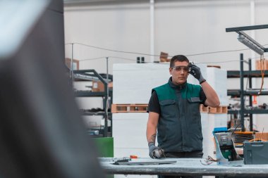 Heavy Industry Engineering Factory Interior with Industrial Worker Using Angle Grinder and Cutting a Metal Tube. Güvenlik Üniforması ve Sert Şapka Üretim Metal Yapıları Müteahhiti. Yüksek kalite